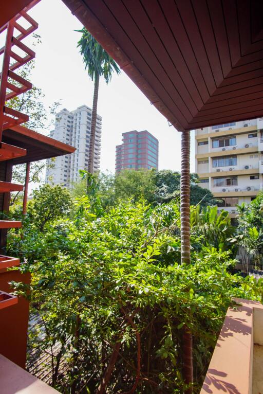 View from balcony with greenery and distant buildings