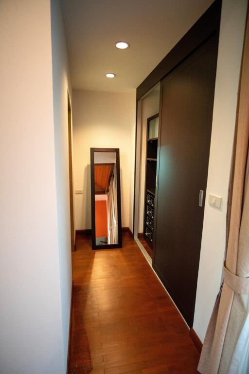 Narrow hallway with wooden floor and recessed lighting