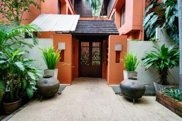 Entrance of a residential building with plants and decorative vases