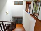 Bright staircase area with wooden flooring and large windows