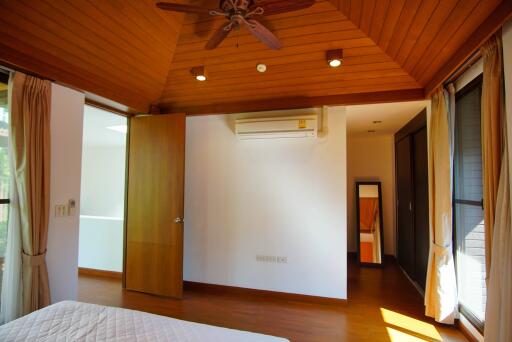 Spacious bedroom with wooden ceiling and ceiling fan