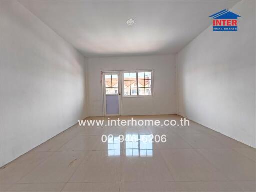 Empty room with tiled floor, large window and white walls