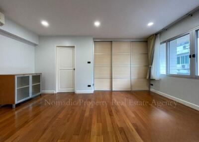 Spacious bedroom with wooden flooring and built-in storage