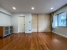 Spacious bedroom with wooden flooring and built-in storage