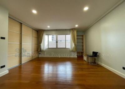 Spacious bedroom with wooden flooring and large window