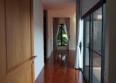 View of a hallway with wooden flooring, large windows, and curtains.