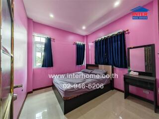 Spacious bedroom with bright pink walls, large bed, and windows with dark blue curtains