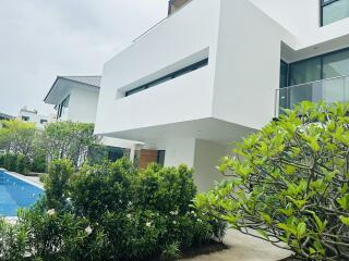 Modern white exterior with pool and greenery