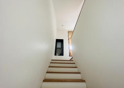 A modern staircase leading to an upper floor with white walls and wooden steps