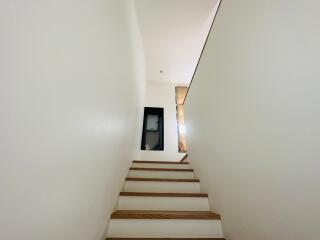 A modern staircase leading to an upper floor with white walls and wooden steps