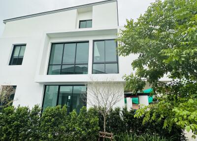 Modern three-story building with large windows and surrounding greenery