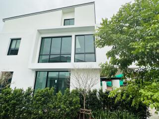 Modern three-story building with large windows and surrounding greenery