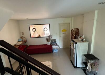 A cozy living room with a red sofa, decorative items, and visible staircase