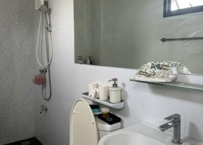 Modern bathroom with toilet, sink, mirror, and shower