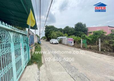 Residential street view with a gate, flag, and contact information