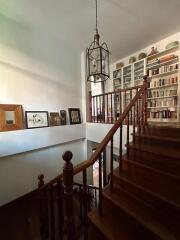 Elegant staircase with wooden railing and hanging light fixture