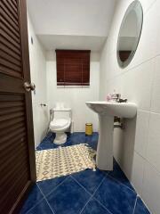 Bathroom with blue tile flooring, round mirror, and wooden blinds