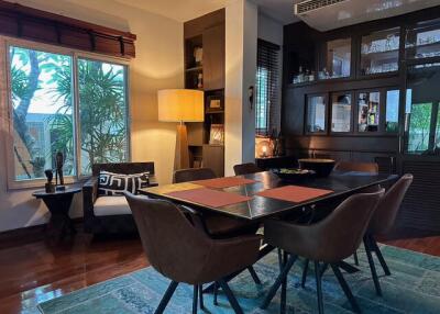 Dining room with a large window, bookshelf, and wooden furniture.