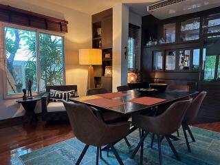 Dining room with a large window, bookshelf, and wooden furniture.