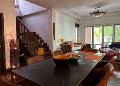 Living and dining area with staircase, seating, and natural light