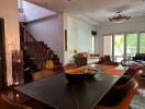 Living and dining area with staircase, seating, and natural light