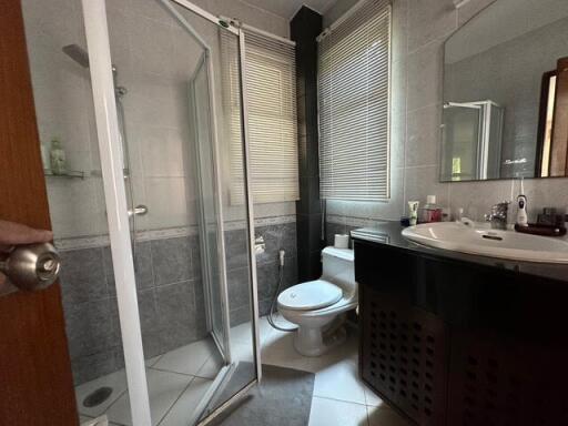 Compact bathroom with a glass-enclosed shower, toilet, and sink with a large mirror.