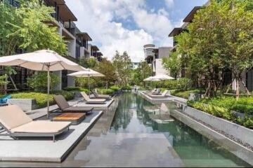 Outdoor swimming pool area with lounge chairs and umbrellas in a residential complex.