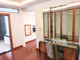 Bright bedroom with wooden floor, mirrored vanity table, built-in closet, and natural light