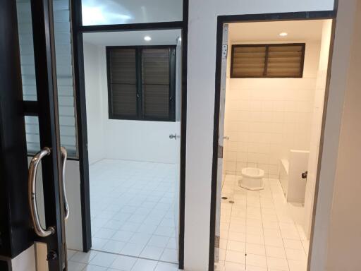 Interior view of two rooms with tiled floors and windows, including a bathroom