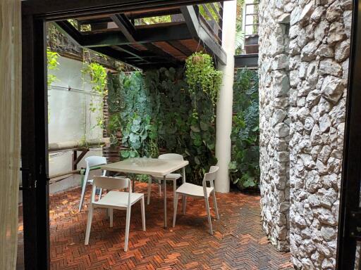 A covered patio with a table and chairs set against a green wall