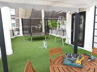 Outdoor terrace with artificial grass, trampoline, and seating area