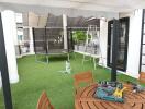 Outdoor terrace with artificial grass, trampoline, and seating area