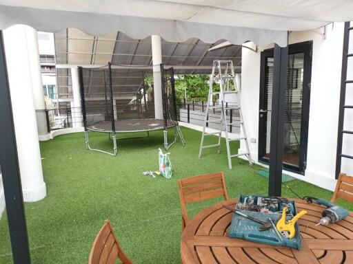 Outdoor terrace with artificial grass, trampoline, and seating area