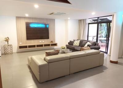 Modern living room with sofas, TV, and glass door to the patio