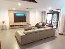 Modern living room with sofas, TV, and glass door to the patio