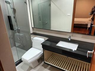 Modern bathroom with glass shower, sink, toilet, and large mirror