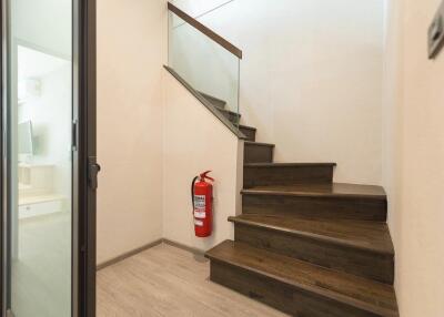 Staircase with wooden steps, glass railing, and fire extinguisher