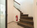 Staircase with wooden steps, glass railing, and fire extinguisher