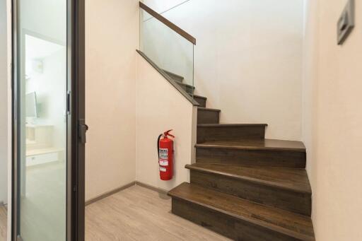 Staircase with wooden steps, glass railing, and fire extinguisher