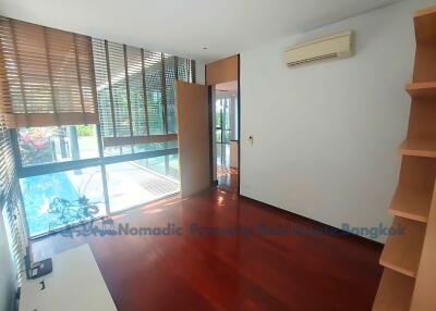 Bright living room with wooden flooring, large windows, and a pool view