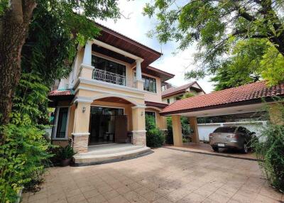 Front view of a house with a driveway, garage, and lush greenery