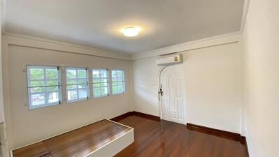 Bright bedroom with wooden flooring and multiple windows