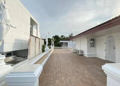 Outdoor walkway of a modern building with statues and white columns