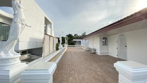 Outdoor walkway of a modern building with statues and white columns