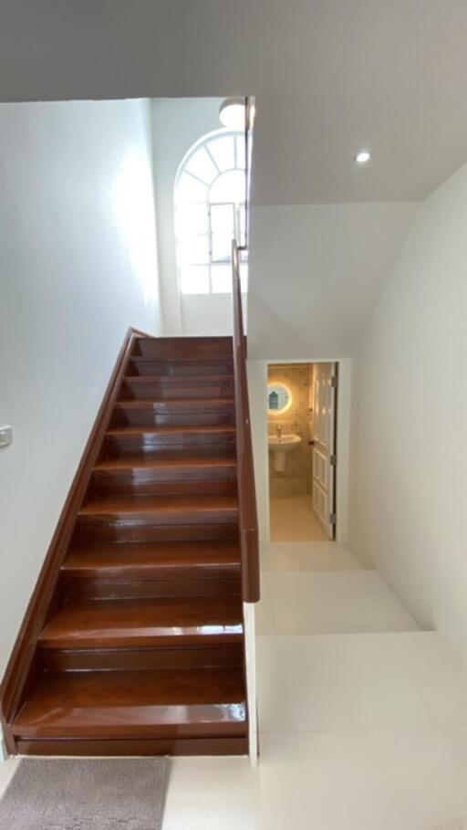 Staircase and view of a hallway with natural lighting.