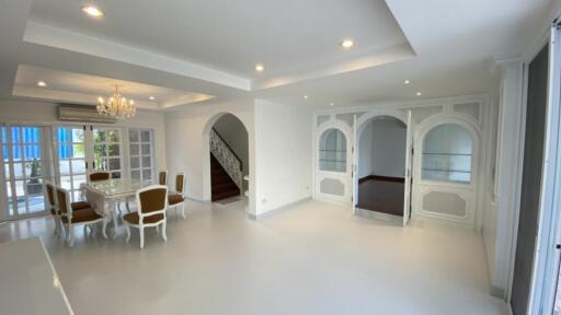 Spacious and bright living and dining area with chandelier, large windows, and elegant doors