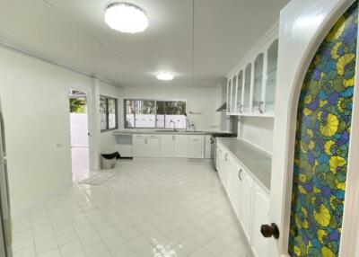 Spacious kitchen with white cabinets and stained glass door