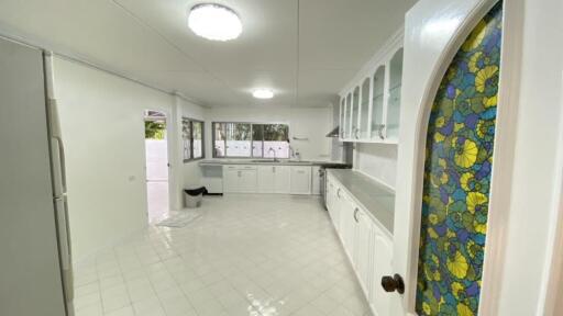 Spacious kitchen with white cabinets and stained glass door