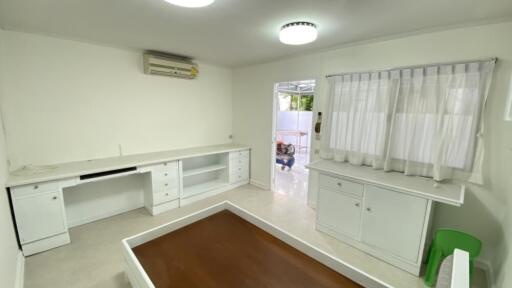 Bright room with white furniture, an air conditioning unit, and a window with curtains