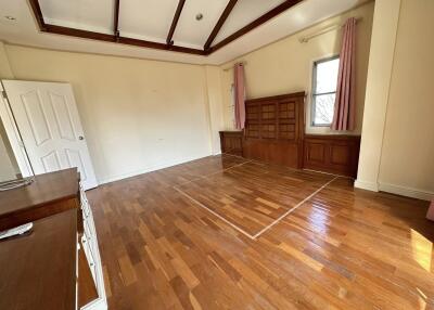 Spacious bedroom with wooden flooring and large windows